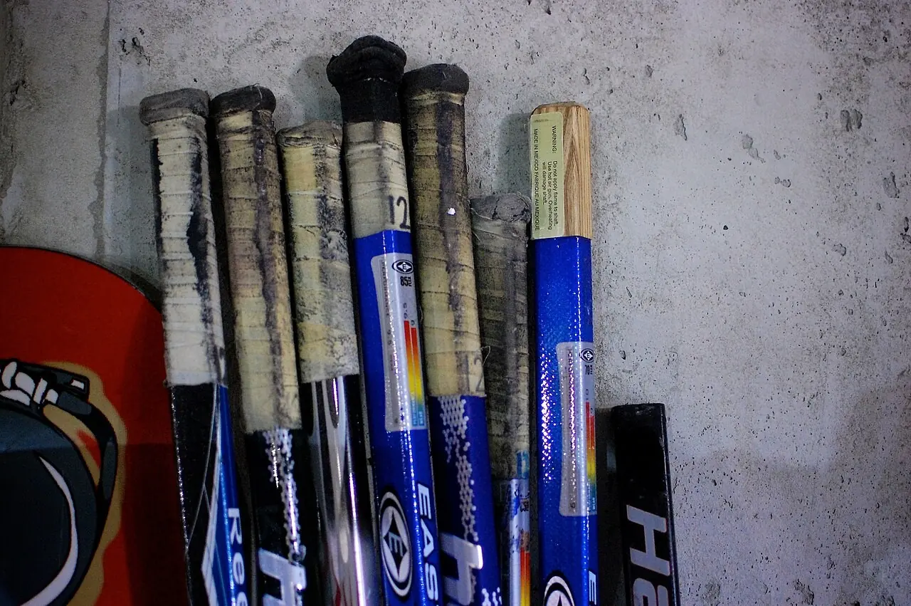 Worn hockey stick handles leaning against a wall