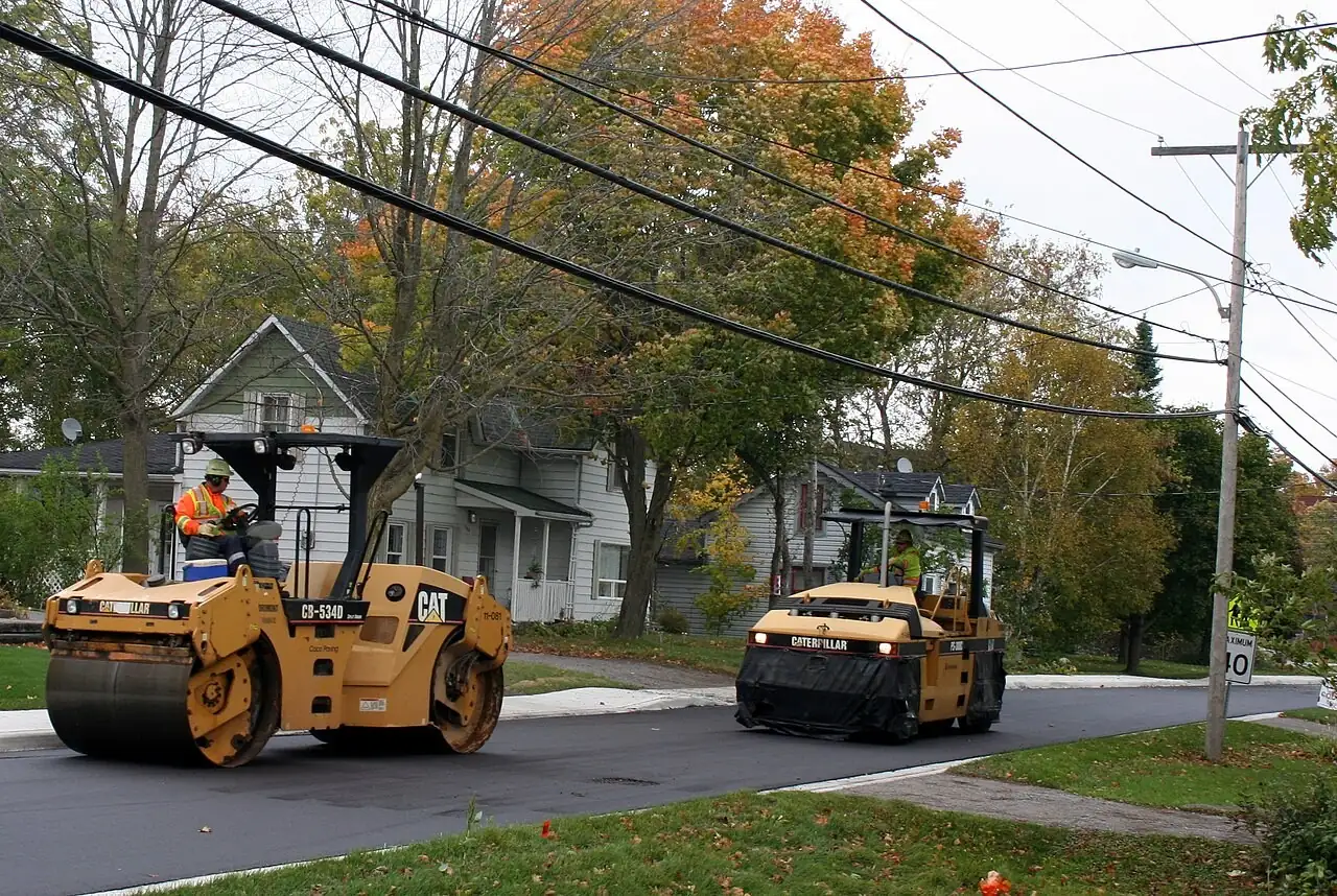 Two road rollers finishing new asphalt on a residential street