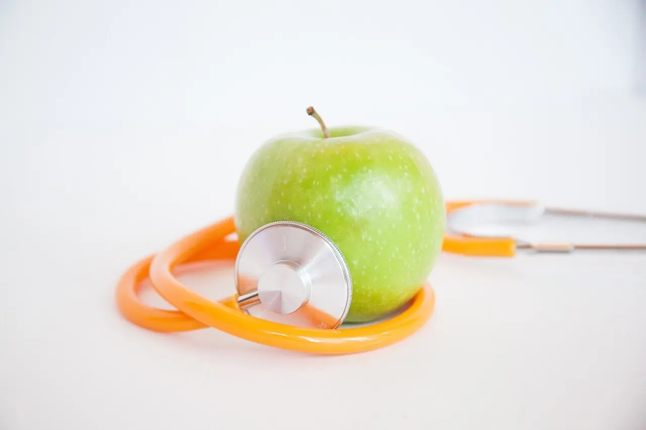 Green apple with a stethoscope wrapped around it