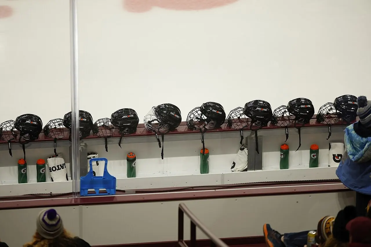 Helmets and water bottles lined up on a hockey bench