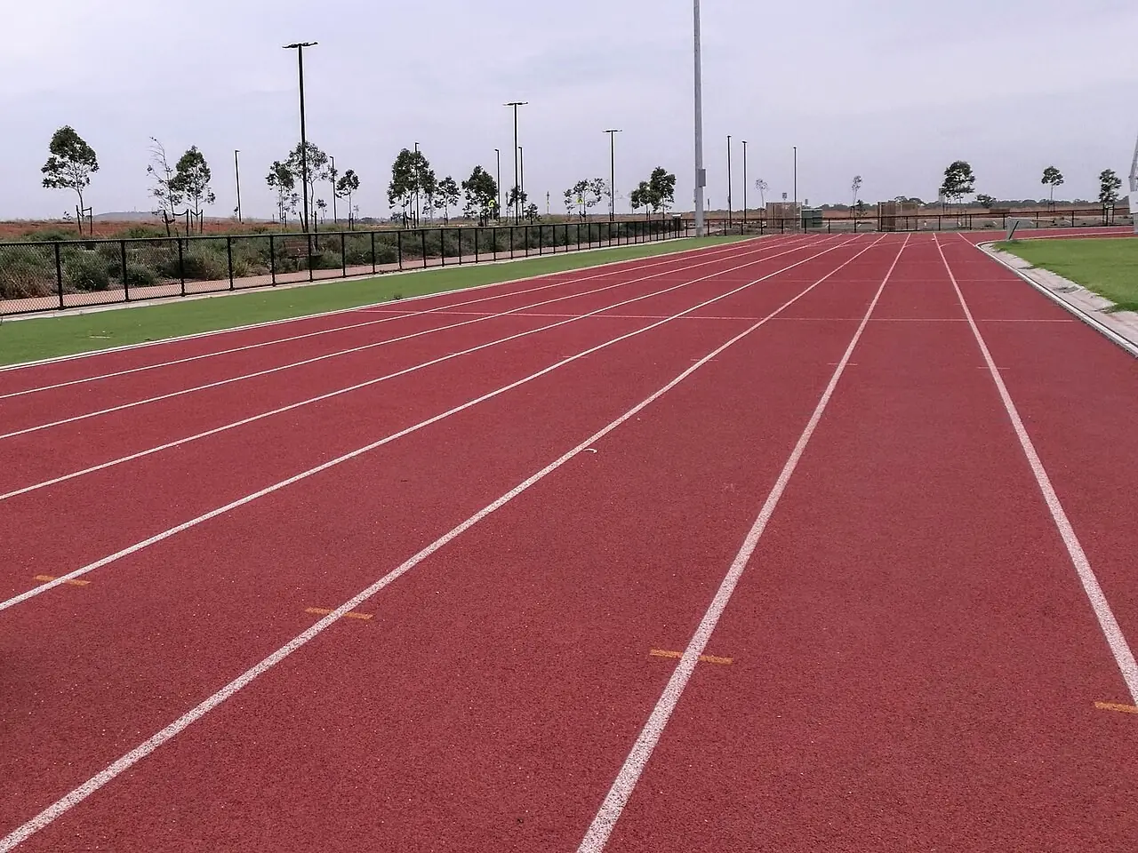 Empty lanes of a new running track under a cloudy sky