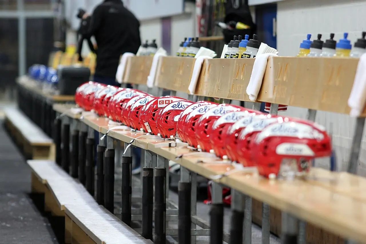 Row of red hockey helmets on a team bench