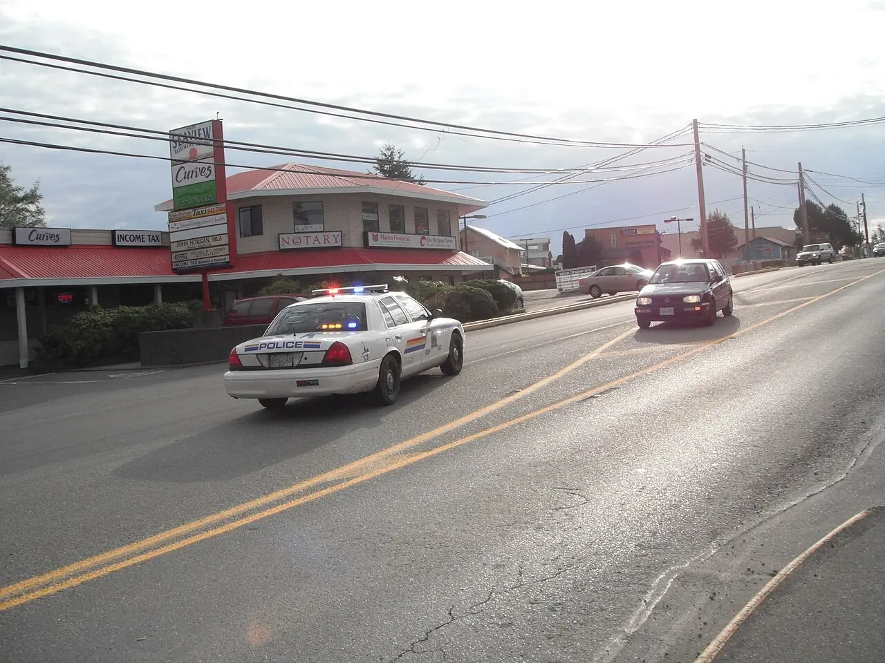 RCMP cruiser with lights on driving on a road