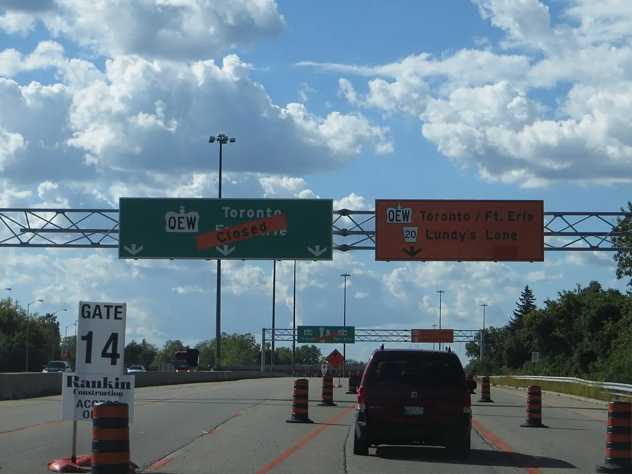 Overhead detour sign and barrels on a highway ramp