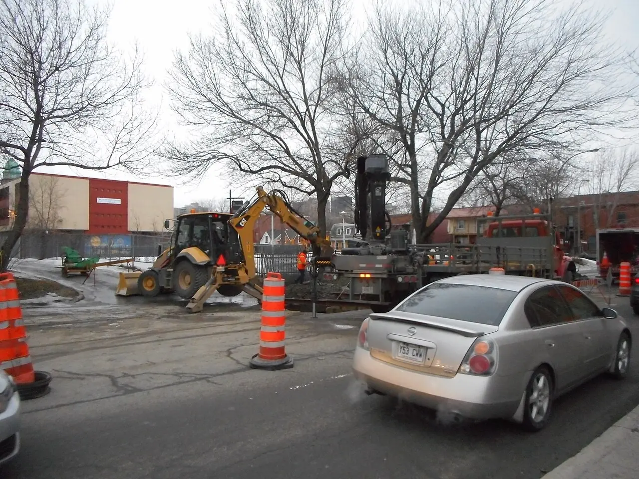 Backhoe repairing a water main break on a city street