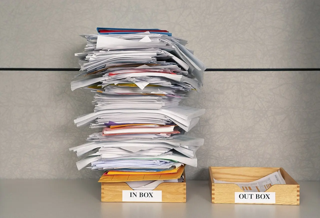 Stack of paperwork in an overflowing inbox tray