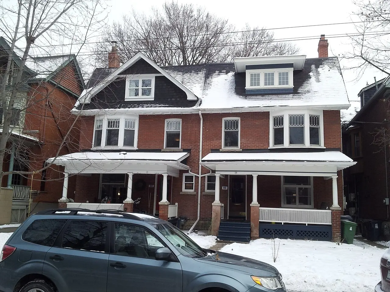 Red brick Victorian row houses with parked cars