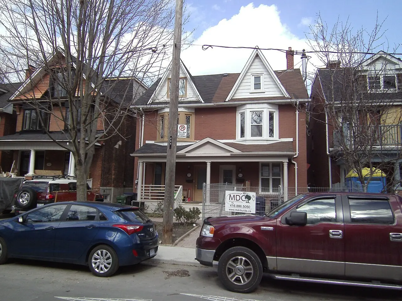 Row of brick houses with parked cars on a residential street