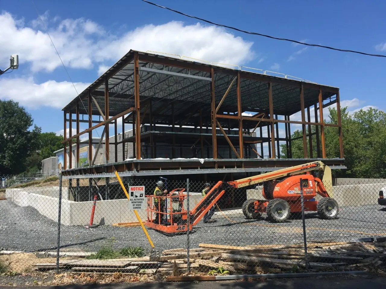 Steel frame of a new building behind construction fencing